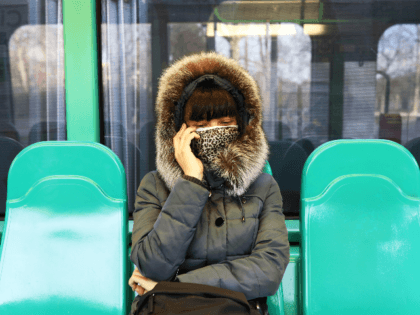 A woman hiding a protective mask under a scarf is seen in the public transportation on Feb