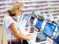 Pretty young woman checking the latest laptop computer in an electronic store