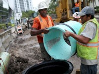 MIAMI BEACH, FL - SEPTEMBER 25: Reluss Williams (L) and other construction workers install a drainage pipe that will be attached to a water pump station being built by the City of Miami Beach in the street on September 25, 2014 in Miami Beach, Florida. As climate change brings higher …
