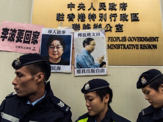 Police walk past missing person notices of Gui Minhai (L), one of five missing booksellers