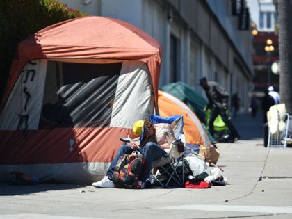A homeless man sleeps in front of his tent along Van Ness Avenue in downtown San Francisco, California on June, 27, 2016. Homelessness is on the rise in the city irking residents and bringing the problem under a spotlight. (Photo by Josh Edelson / AFP) (Photo credit should read JOSH …