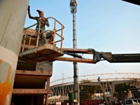 A worker paints a pillar of the under construction metro rail project, outside the Motera Cricket Stadium, on the outskirts of Ahmedabad on February 16, 2020. - A barbed wire topped wall that will hide Donald Trump's cavalcade from a slum and the world's biggest cricket stadium are just two …