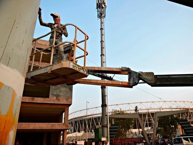 A worker paints a pillar of the under construction metro rail project, outside the Motera