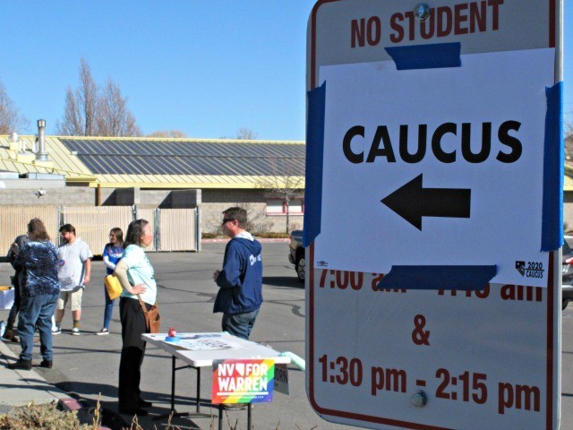Volunteers for various campaigns talk to voters as they enter a presidential caucus site a