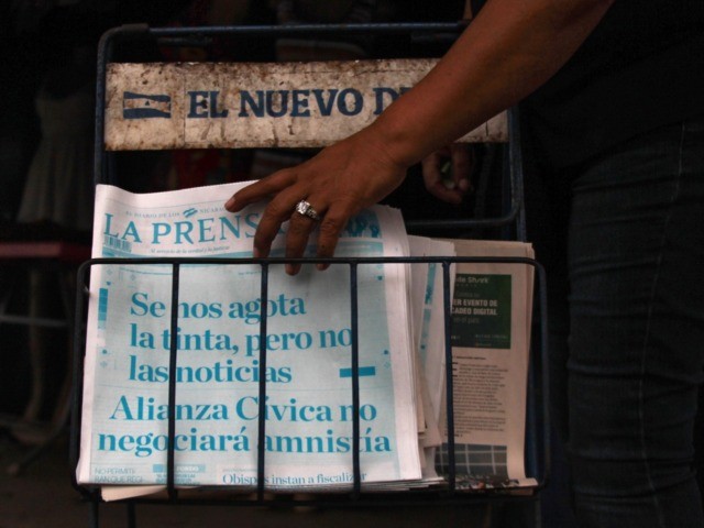 A passer-by gets an edition of "La Prensa" newspapers which printed its cover in cyan with the headline "We are running out of ink, but not of news. The Civic Alliance will not negociate an amnesty", at a newsstand in Managua, on March 25, 2019. - Paper and ink imported …
