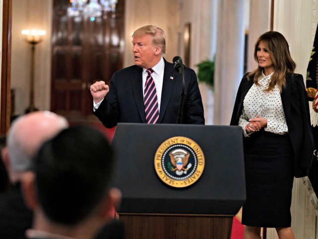 First lady Melania Trump looks on as President Donald Trump pumps his fist after speaking