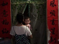 TOPSHOT - In this picture taken on October 12, 2016, a woman holds a baby as she walks through a door to enter her house in Sanya. / AFP / NICOLAS ASFOURI (Photo credit should read NICOLAS ASFOURI/AFP via Getty Images)