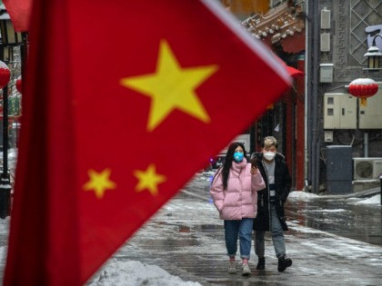 BEIJING, CHINA - FEBRUARY 05: A Chinese couple wear protective masks as they walk during a snowfall in an empty and shuttered commercial street on February 5, 2020 in Beijing, China. China's stock markets tumbled in trading on Monday, the first day back after an extended Lunar New Year holiday …
