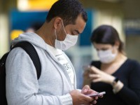 Passengers wearing masks as a precaution against the spread of the new coronavirus COVID-19 use their phones at the Sao Paulo International Airport in Sao Paulo, Brazil, Thursday, Feb. 27, 2020. (AP Photo/Andre Penner)