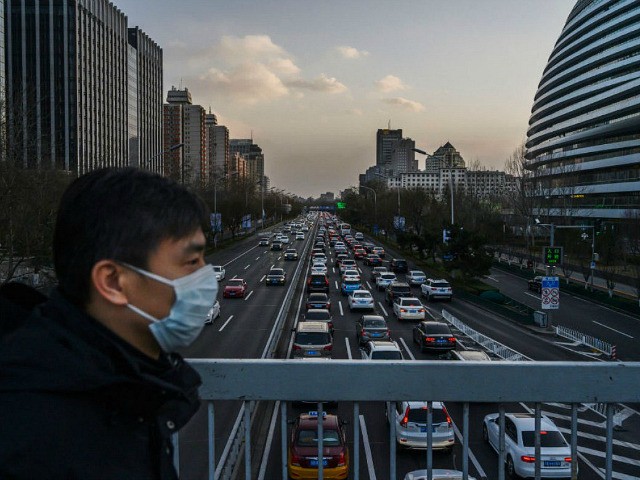 BEIJING, CHINA - FEBRUARY 21: A Chinese man wears a protective mask as he crosses a footbridge over the 2nd Ring Road during a busier rush hour than in the last weeks on February 21, 2020 in Beijing, China. The number of cases of the deadly new coronavirus COVID-19 being …