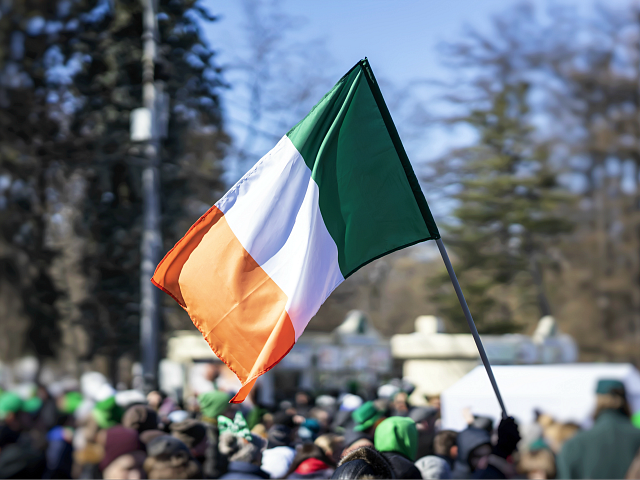 Flag of Ireland close-up in hands on background of blue …