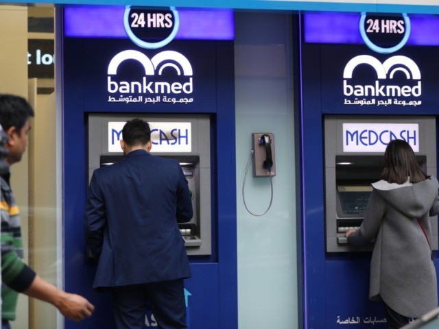 A Lebanese men withdraw money from a ATM in the capital Beirut on December 30, 2019 as the