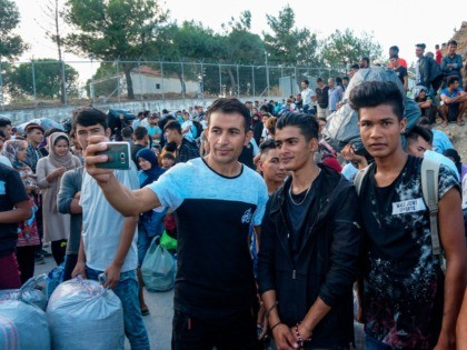 Refugees and migrants take selfie outside the Moria hotspot on the island of Lesbos, prior to their transfer to the island port and then to the country's mainland on October 6, 2019. - Hundreds of refugees and migrants will be relocated in camps in northern Greece from the overcrowded Moria …