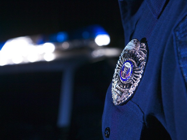 Close-up of an officer's badge with the police lights on the car flashing in the background - stock photo