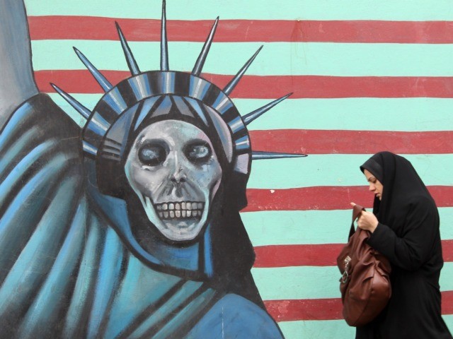 An Iranian woman walks past an anti-US mural painted on the wall of the former US embassy in Tehran on November 19, 2011. The United States said Iran was now locked in "unprecedented" isolation after UN bodies overwhelmingly condemned its nuclear programme and an alleged Tehran-planned terror plot. AFP PHOTO/ATTA …