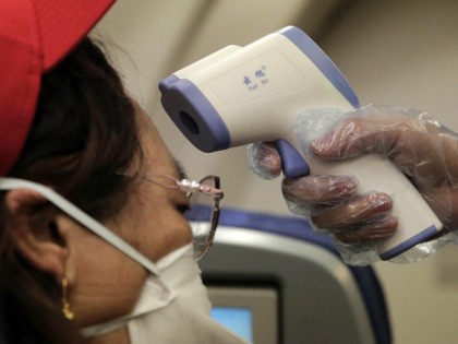 A stewardess takes the temperature of passenger as a preventive measure for the coronaviru