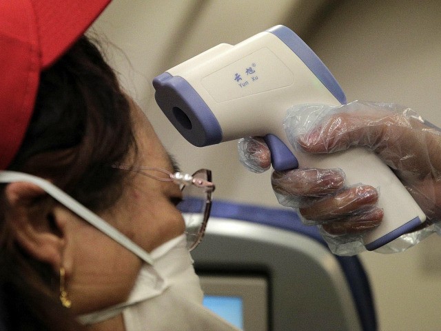 A stewardess takes the temperature of passenger as a preventive measure for the coronavirus on an Air China flight from Melbourne to Beijing before it land at Beijing Capital International Airport in China, Tuesday, Feb. 4, 2020. China said Tuesday the number of infections from a new virus surpassed 20,000 …
