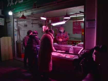 TOPSHOT - A vendor (R) offers meat to customers, wearing facemasks to help stop the spread