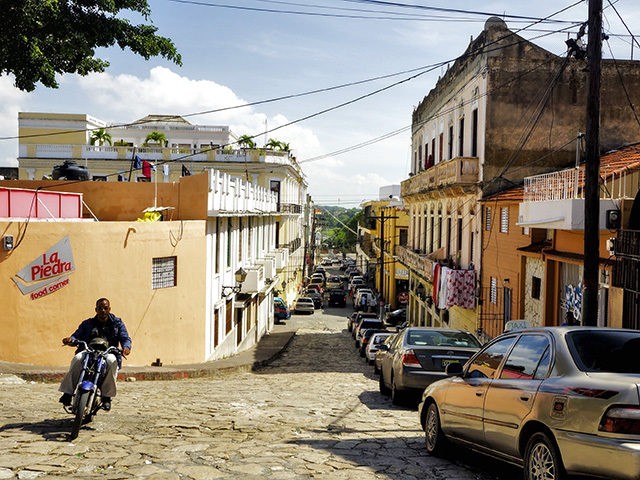 A man rides his motorcycle through an empty street in Santo Domingo, the capital and large