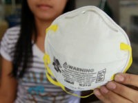 In a May 6, 2009 file photo a store attendantholds an N-95 mask over a box of disposable surgical masks in Manila, Philippines. Health workers caring for patients who have or may have swine flu should wear a special type of mask called an N95 respirator, not looser-fitting surgical masks, …