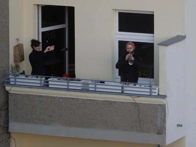 A man plays Beethoven's Ode of Joy on his trumpet on a balcony at the district Prenzlauer