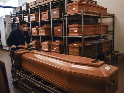 A worker takes away a coffin in the Crematorium Temple of Piacenza, Northern Italy, saturated with corpses awaiting cremation due to the coronavirus emergency Monday, March 23, 2020. For most people, the new coronavirus causes only mild or moderate symptoms. For some it can cause more severe illness, especially in …