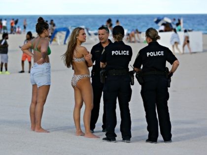 Tabatha Hannah, a student at St. Clair Community College, center, talks with Miami Beach police officers during spring break, Saturday, March 14, 2020, in Miami Beach, Fla. Portions of South Beach were closed late Saturday to avoid large group gatherings that could spread the coronavirus. South Beach is a popular …
