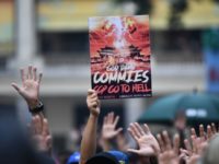 A protester holds up a placard that reads "God damn commies, CCP (Chinese Communist Party) go to hell" as others hold up their hands to signify their five demands at a rally in the Wanchai district of Hong Kong on October 1, 2019, as the city observes the National Day …