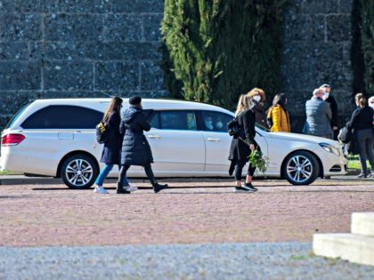 A hearse transporting a coffin enters the Monumental cemetery of Bergamo, Lombardy, as relatives of a deceased person walk outside on March 16, 2020, while burials of people who died of the new coronavirus are being conducted at the rythm of one every half hour. (Photo by Piero Cruciatti / …