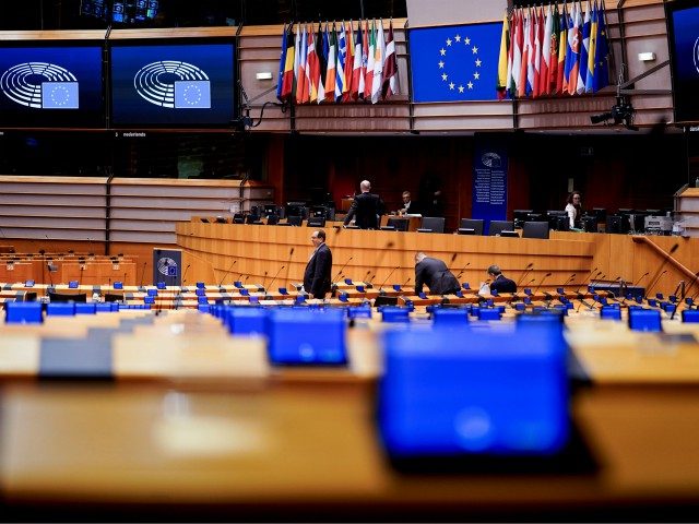 Members of the EU Parliament arrive and sit in an empty hemicycle at the beginning of the