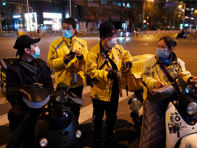 Food delivery riders wearing facemasks amid concerns over the spread of the COVID-19 novel coronavirus, wait for delivery assignments outside a restaurant in Beijing on March 20, 2020. (Photo by GREG BAKER / AFP) (Photo by GREG BAKER/AFP via Getty Images)