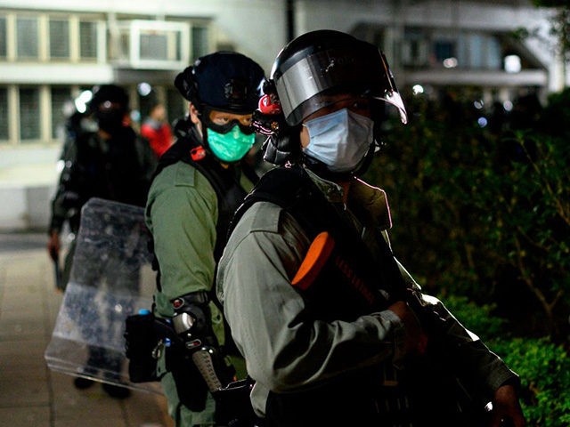 Riot police officers wearing face masks stand guard as residents protest against plans for an empty local housing estate to become a temporary quarantine camp for patients and frontline medical staff of a SARS-like virus outbreak which began in the Chinese city of Wuhan, in the Fanling district in Hong …