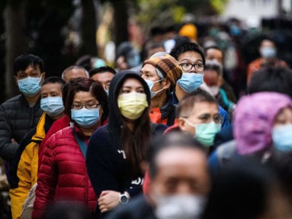 TOPSHOT - People wearing facemasks as a preventative measure following a coronavirus outbreak which began in the Chinese city of Wuhan, line up to purchase face masks from a makeshift stall after queueing for hours following a registration process during which they were given a pre-sales ticket, in Hong Kong …