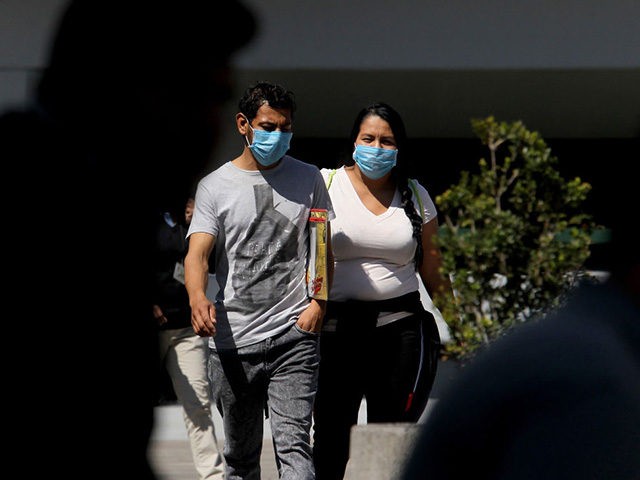 A man and a woman walking in the streets of Guadalajara, Mexico, wear protective face mask