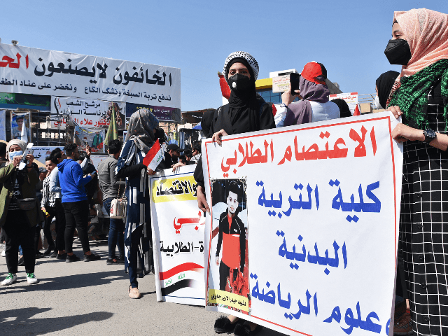 Women student protesters wearing protective face masks stand with a sign during an anti-government demonstration in Iraq's southern city of Nasiriyah in Dhi Qar province on March 1, 2020. (Photo by Asaad NIAZI / AFP) (Photo by ASAAD NIAZI/AFP via Getty Images)