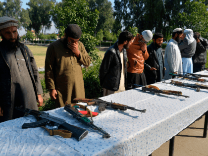 Former Afghan Taliban fighters stand next to weapons before handing them over as part of a government peace and reconciliation process at a ceremony in Jalalabad on March 1, 2020. - The United States signed a landmark deal with the Taliban on February 29, laying out a timetable for a …