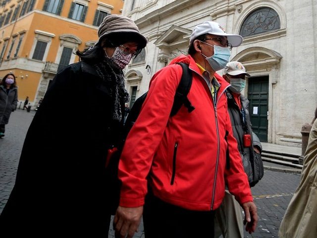 Asian tourists wearing protective masks walk past the Church of St. Louis of the French (San Luigi dei Francesi) in Rome on March 1, 2020. - The French community church closed its doors to the public on March 1, reportedly after a priest was infected with COVID-19 (novel Coronavirus). (Photo …