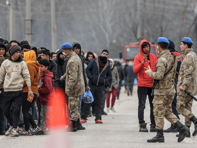 Migrants wait next Turkish soldiers as they resumed efforts to enter Europe next to the fe