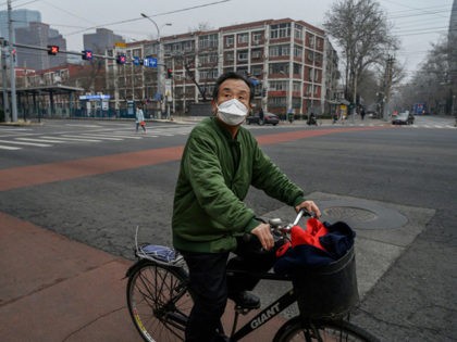 BEIJING, CHINA - MARCH 06: A Chinese commuter wears a protective mask while riding through a nearly empty intersection during the afternoon rush hour on March 6, 2020 in Beijing, China. The number of cases of the deadly new coronavirus COVID-19 being treated in China dropped to below 26,000 in …