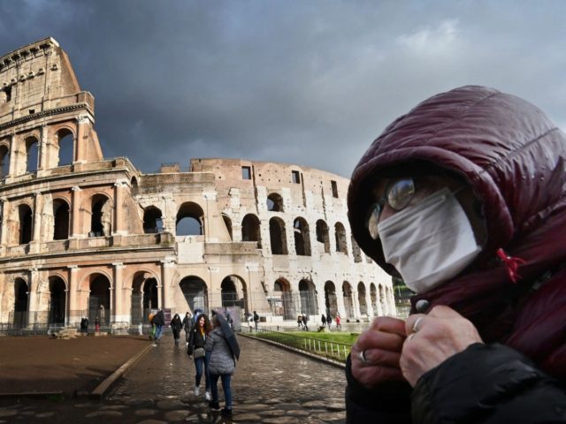 TOPSHOT - A man wearing a protective mask passes by the Coliseum in Rome on March 7, 2020