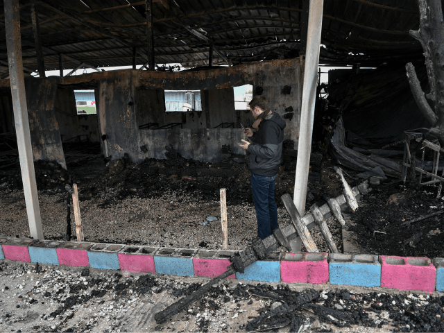 A volunteer teacher takes pictures on March 8, 2020 in the rubbles of the school building of a One Happy Family, a Swiss-operated family care centre for refugees just outside the island of Lesbos capital Mytilene, a day after it burns following violence as Greece announced further restrictions towards asylum …