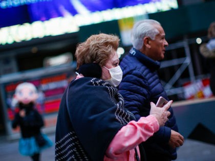 A woman walks by Times Square as she wears a face mask on March 8, 2020 in New York City.