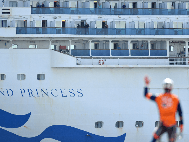 A bicyclist waves to passengers aboard the Grand Princess cruise ship as it docks at the P