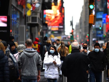 Tourists with protective face masks walk through Times Square on March 13, 2020 in New York City. - The World Health Organization said Friday it was not yet possible to say when the COVID-19 pandemic, which has killed more than 5,000 people worldwide, will peak. "It's impossible for us to …