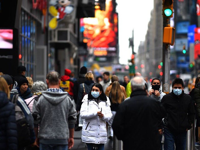 Tourists with protective face masks walk through Times Square on March 13, 2020 in New Yor