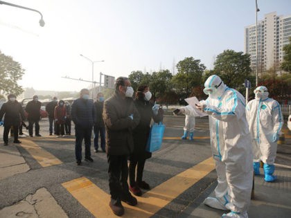 Medical workers (R) check patients who recovered from the COVID-19 coronavirus as they arr