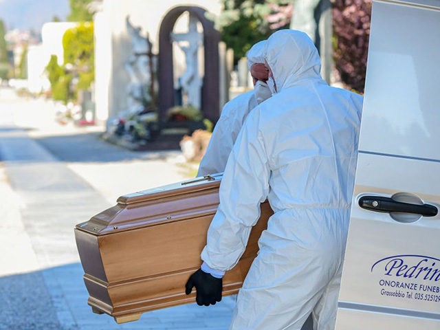 Undertakers wearing a face mask and overalls unload a coffin out of a hearse on March 16, 2020 at the Monumental cemetery of Bergamo, Lombardy, as burials of people who died of the new coronavirus are being conducted at the rythm of one every half hour. (Photo by Piero Cruciatti …