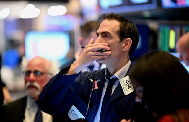 Traders work during the opening bell at the New York Stock Exchange (NYSE) on March 16, 2020 at Wall Street in New York City. - Trading on Wall Street was halted immediately after the opening bell Monday, as stocks posted steep losses following emergency moves by the Federal Reserve to …