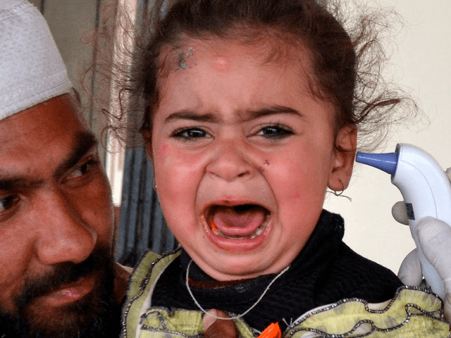 A man holds his daughter as a health official checks her body temperature amid concerns ov