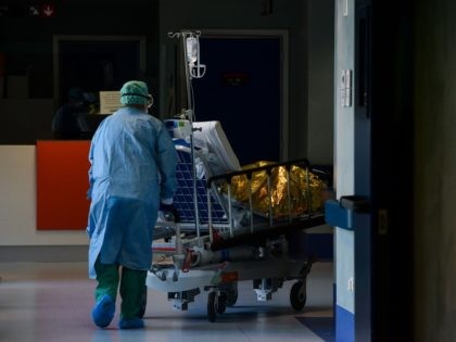 A medical worker wearing a face mask brings a patient arriving on a stretcher at the new c